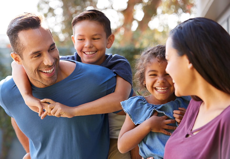 Family of four smiling outside.